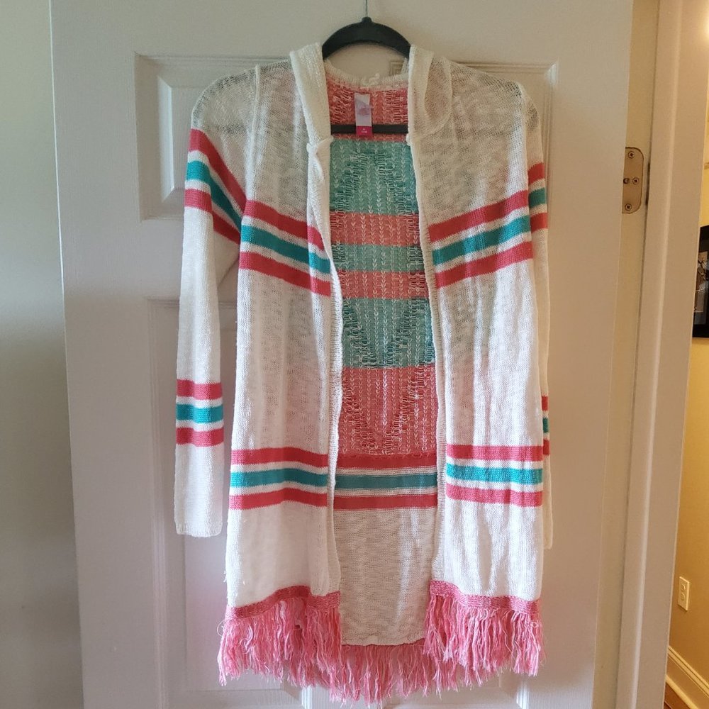 White sweater with green and pink stripes and pink fringe.